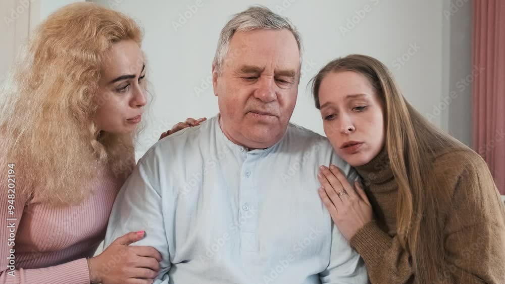 Loving adult daughters comforting sad senior father, hugs him while sitting on the bed. Women caring older man at home. Family support and relationship, caring and children love concept Loving adult daughters comforting sad senior father, hugs him while sitting on the bed. Women caring older man at home. Family support and relationship, caring and children love concept