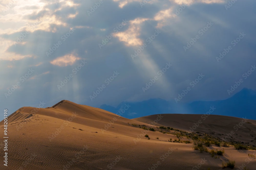 Fototapeta premium Dramatic desert dunes under sunbeams and cloudy sky
