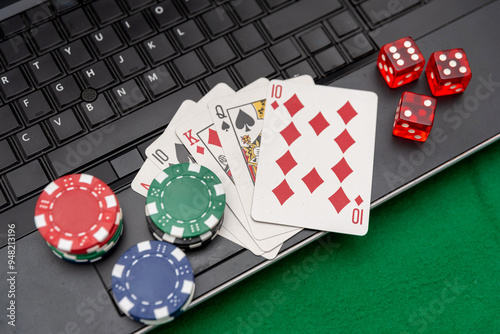 Poker Chips, Playing Cards, and Red Dice on a Laptop Keyboard, online gamble concept photo