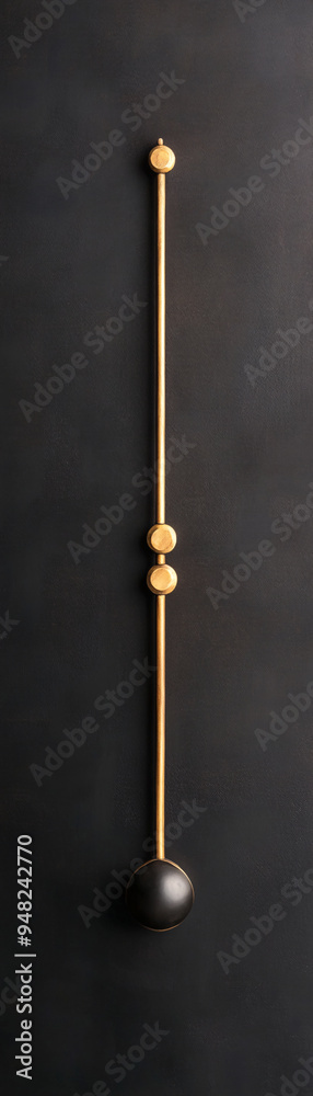 A gold and black object with a black ball on top of it. The object is hanging from a wall A gold and black object with a black ball on top of it. The object is hanging from a wall