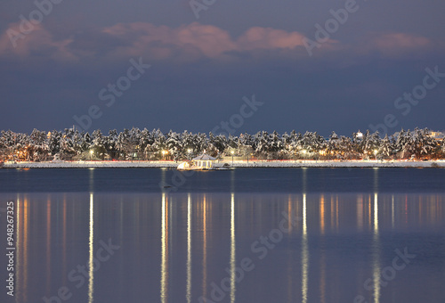 Gangneung-si, Gangwon-do, South Korea - December 25, 2021: Winter and night view of a pavilion on Gyeongpo Lake with street lights and now covered trees photo