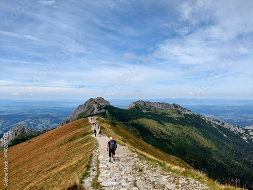 Fototapeta Naklejka Na Ścianę i Meble -  Hikers enjoying the view while walking on a mountain ridge hiking trail in tatra national park, Giewont, Tatra national park, Poland