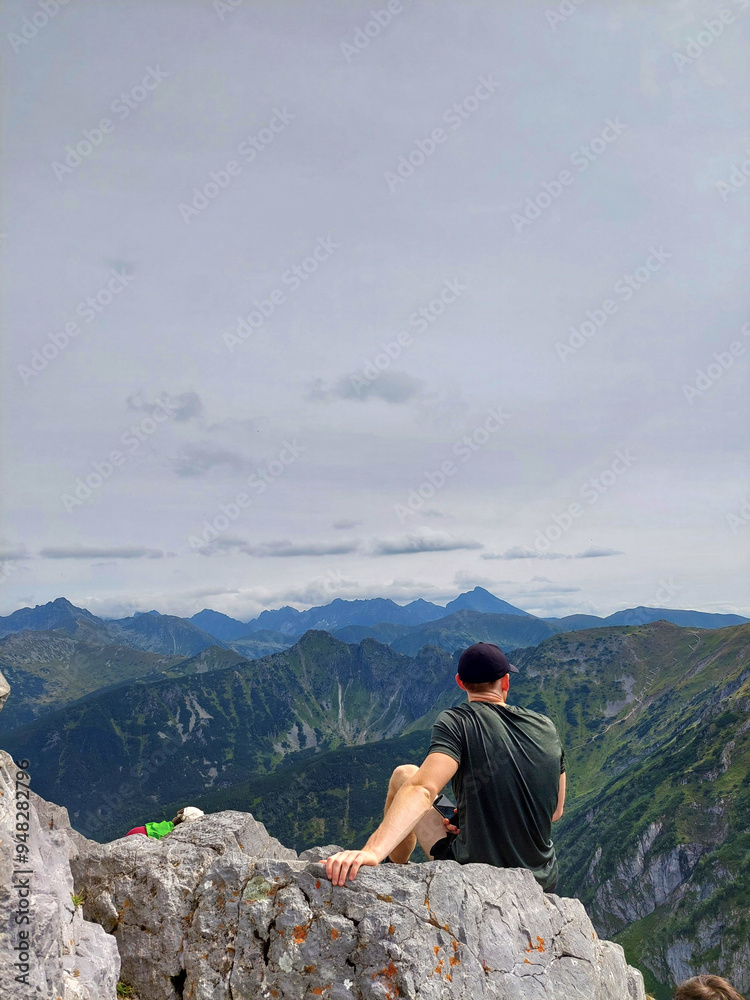 Hiker is enjoying the breathtaking view of the mountain ranges after reaching the summit, view from Giewont, Tatra national park, Poland Hiker is enjoying the breathtaking view of the mountain ranges after reaching the summit, view from Giewont, Tatra national park, Poland