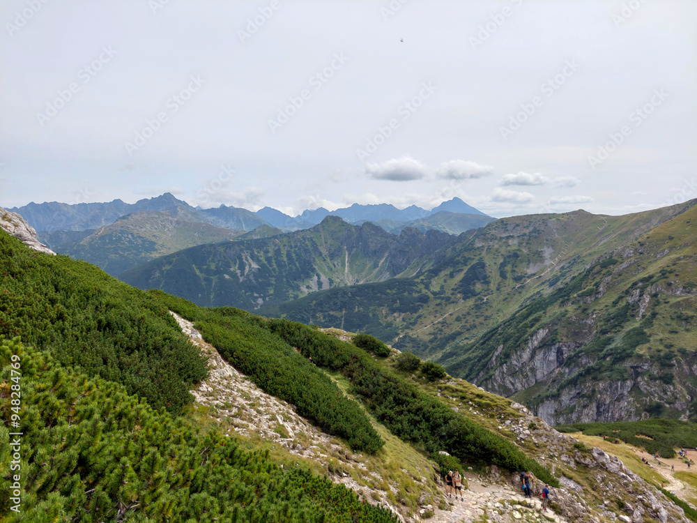 Hikers enjoying a scenic mountain view while walking up a winding trail in the tatra national park Hikers enjoying a scenic mountain view while walking up a winding trail in the tatra national park