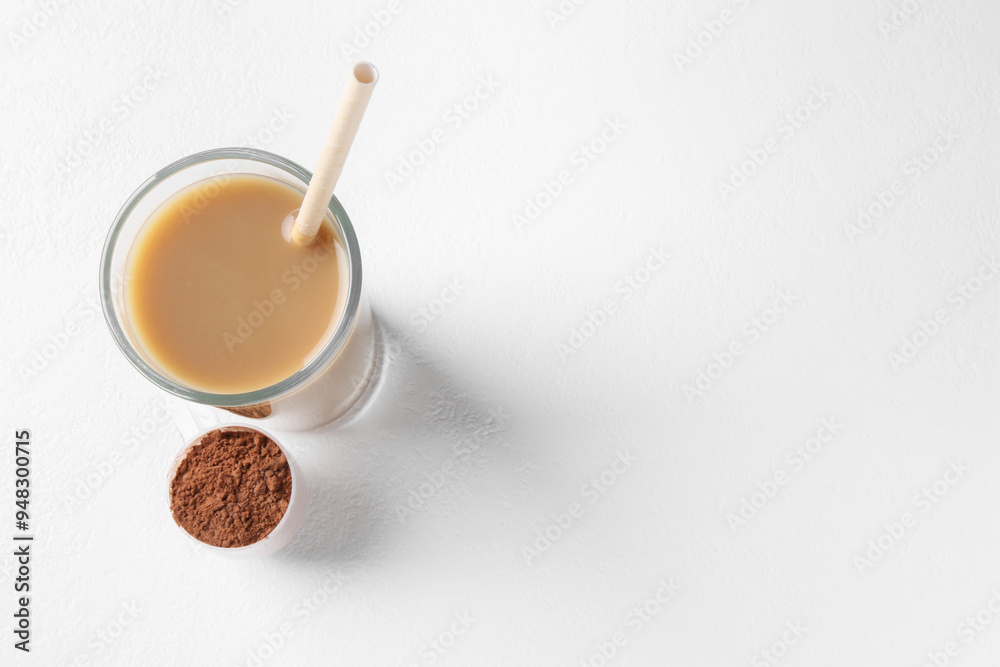 Delicious protein shake in glass and scoop with powder on white background, top view. Space for text Delicious protein shake in glass and scoop with powder on white background, top view. Space for text