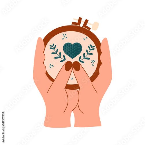 Handmade, cross stitch. Creative work, handicrafts. Women's hands hold a hoop with embroidered flowers and hearts.