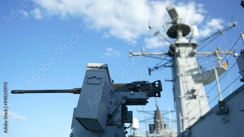 Color image of an automated machine gun on the deck of a military ship, at sea.
