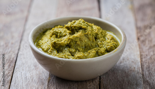 Bowl of green curry paste on a wooden background. Food and spice concept. photo