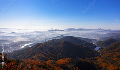 Aerial and Panoramic view of of maple trees on the peak of Gamaksan Mountain against ridges and sea of clouds on farming village near Paju-si, South Korea 