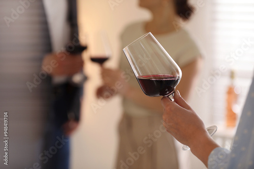 Woman with glass of red wine indoors, selective focus