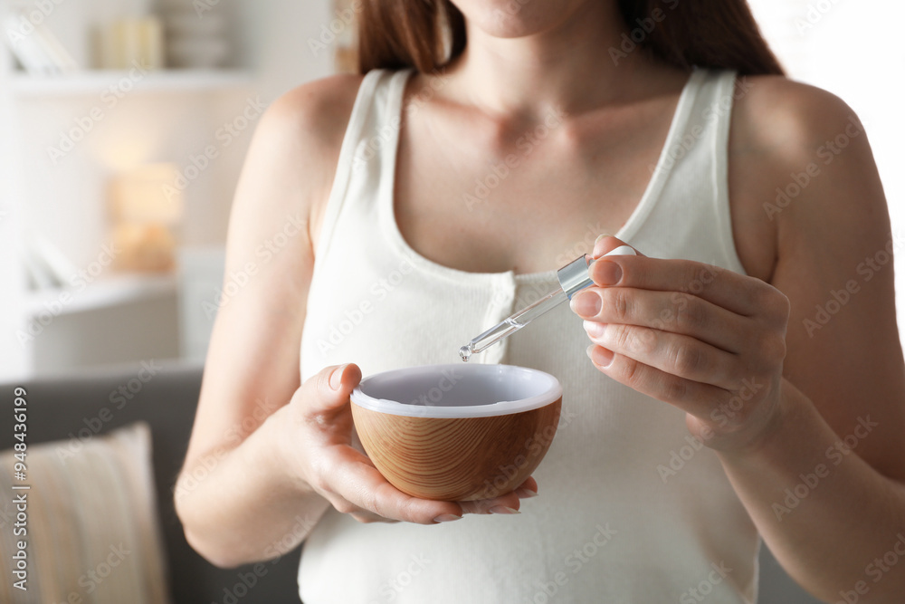 Woman adding essential oil to aroma diffuser at home, closeup Woman adding essential oil to aroma diffuser at home, closeup