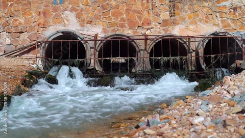 Draining sewage from pipe into river, pollution rivers and ecology. water flowing from a drain pipe into a the sea