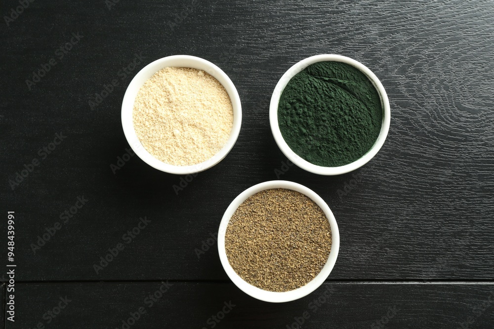 Different healthy superfoods in bowls on black wooden table, flat lay Different healthy superfoods in bowls on black wooden table, flat lay