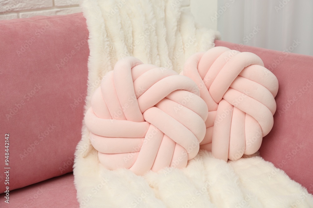 Decorative pillows and fluffy blanket on pink sofa indoors Decorative pillows and fluffy blanket on pink sofa indoors