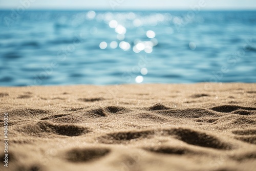 Abstract beach background with blurred bokeh light. Foreground sand is in focus.