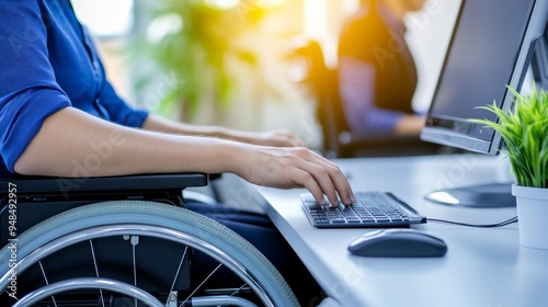 A close-up of a person in a wheelchair typing on a keyboard in a modern office environment photo