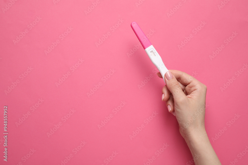 Woman holding pregnancy test on pink background, top view. Space for text Woman holding pregnancy test on pink background, top view. Space for text