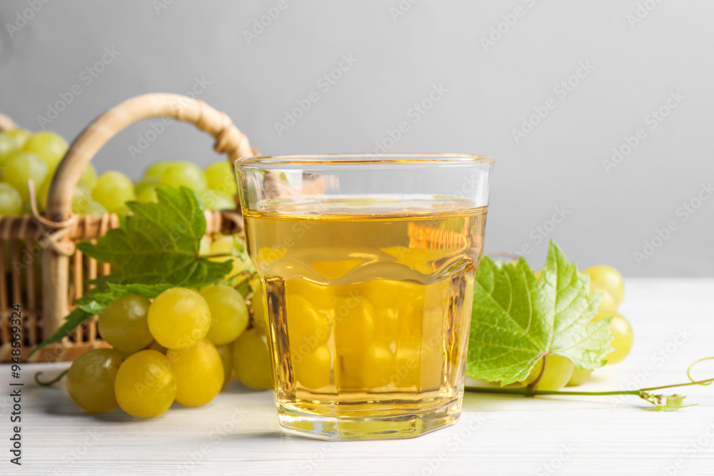 Ripe grapes and glass of tasty juice on white wooden table Ripe grapes and glass of tasty juice on white wooden table