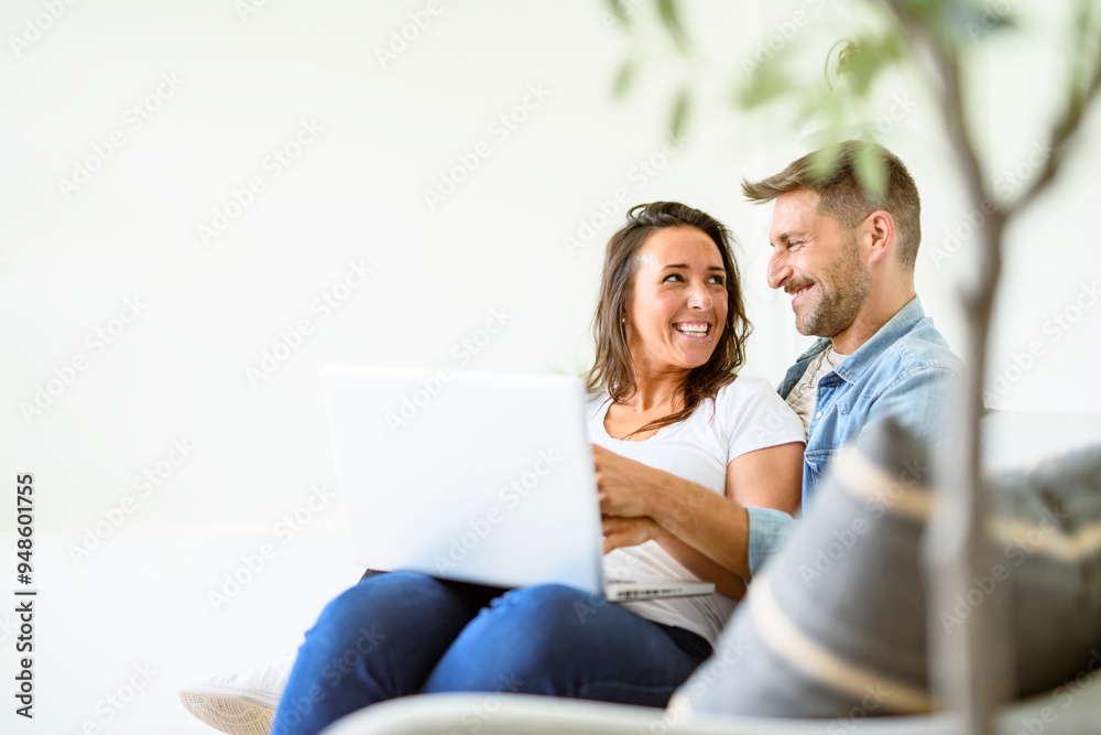 bearded husband cuddling affectionate wife on computer at home. Using laptop in living room. bearded husband cuddling affectionate wife on computer at home. Using laptop in living room.