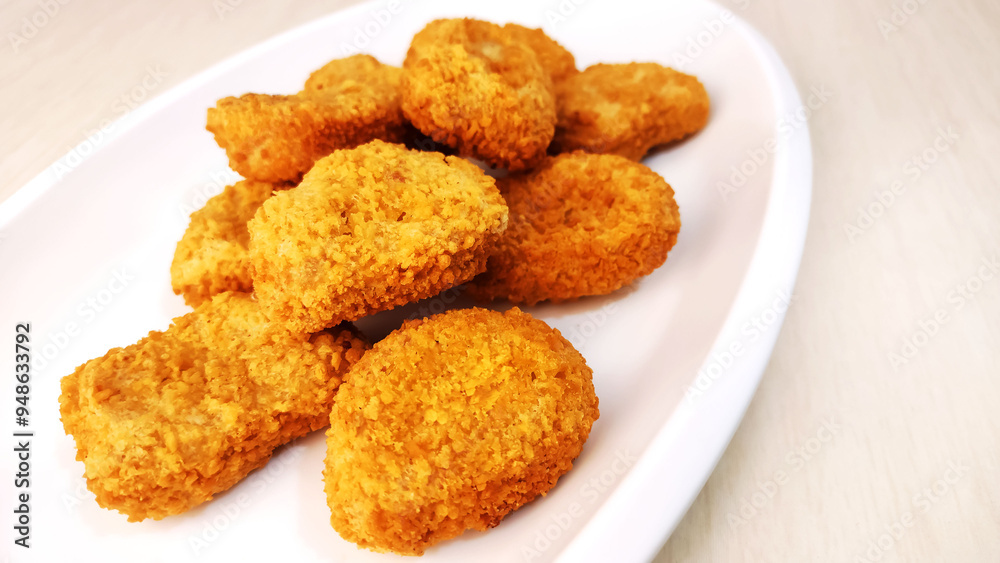 Chicken breast fillet in a crispy breading known as Nuggets on a white plate
Chicken breast fillet in a crispy breading known as Nuggets on a white plate