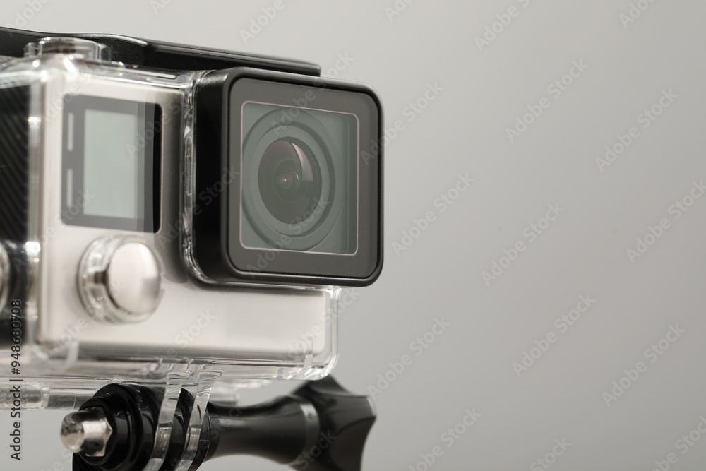 Fototapeta premium Modern action camera and mount on grey background, closeup. Space for text