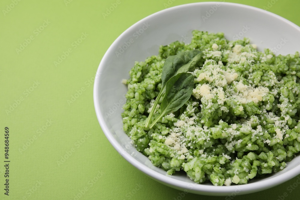 Delicious spinach risotto with parmesan cheese on light green background, closeup. Space for text Delicious spinach risotto with parmesan cheese on light green background, closeup. Space for text