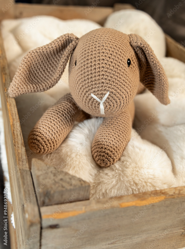 Brown rabbit lying in a wooden box on a sheepskin rug. Brown rabbit lying in a wooden box on a sheepskin rug.