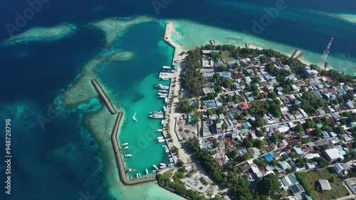 Aerial view of a beautiful local island village with houses, rooftops, harbour, reef, lagoon, and boats, Rashdoo, Maldives. photo