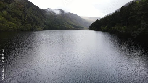A low drone shot of a misty overcast lake. Glendalough, Wicklow, Ireland