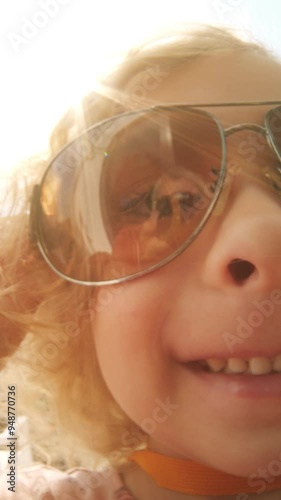 Smiling girl wearing big sunglasses, funny fisheye portrait, vertical video photo