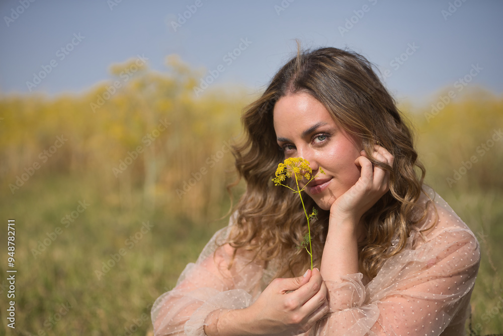 Portrait of a young, beautiful, blonde woman with green eyes, wearing a silk shirt, covering her face with a fennel branch, in the middle of the field. Concept beauty, countryside, peace, nature. Portrait of a young, beautiful, blonde woman with green eyes, wearing a silk shirt, covering her face with a fennel branch, in the middle of the field. Concept beauty, countryside, peace, nature.