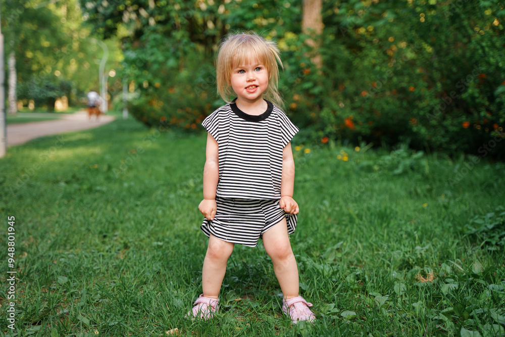 Cute Caucasian toddler child 2-years-old girl walks in a green park at sunset in summer. The concept of a joyful childhood and active pastime. Cute Caucasian toddler child 2-years-old girl walks in a green park at sunset in summer. The concept of a joyful childhood and active pastime.