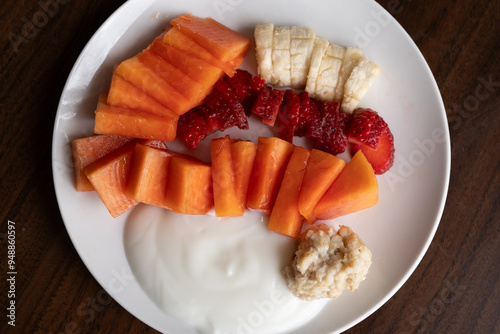 Toma cenital de plato de desayuno con fruta picada sobre mesa de madera con yogurt y avena photo