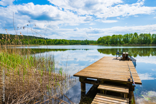 Fishing chair on wooden pier at beautiful lake during sunny summer day, Suwalski Landscape Park, Podlasie, Poland