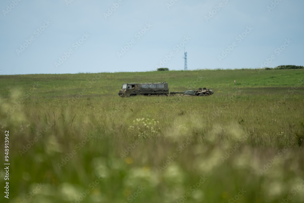 Fototapeta premium British army bae systems, Puch, Daimler, Pinzgauer High-Mobility All-Terrain 6x6 vehicle towing a 105mm Light Artillery Gun on a military exercise