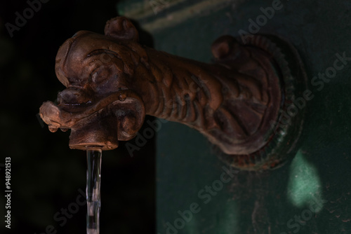 Old tap in the shape of a dragon's head, little public fountain in Milan