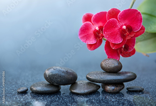 Spa stones and red orchid flowers on the gray table background.