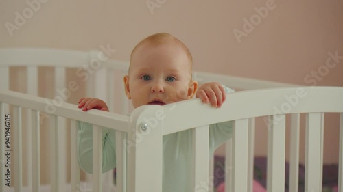 Curious baby stands in crib and explores surroundings in a cozy nursery during morning hours