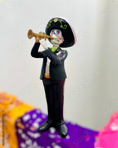 Obraz na płótnie Figura decorativa de una calavera vestida como mariachi, tocando su trompeta, podemos observar que esta sobre papel picado que se utiliza para decorar la famosa ofrenda de día de muertos mexicana