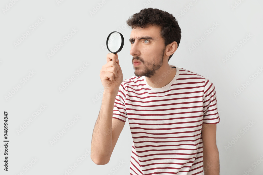 Young man with magnifier on light background Young man with magnifier on light background