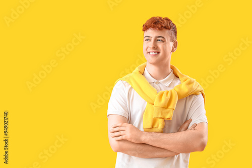 Young redhead man on yellow background