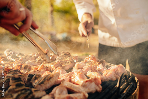 A lively and vibrant outdoor barbecue scene unfolds, with fresh, juicy meat sizzling enticingly on the grill photo