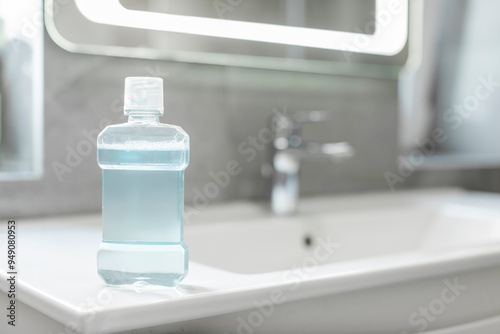 Bottle of fresh mouthwash on washbasin in bathroom, closeup. Toothcare and fresh breath concept photo