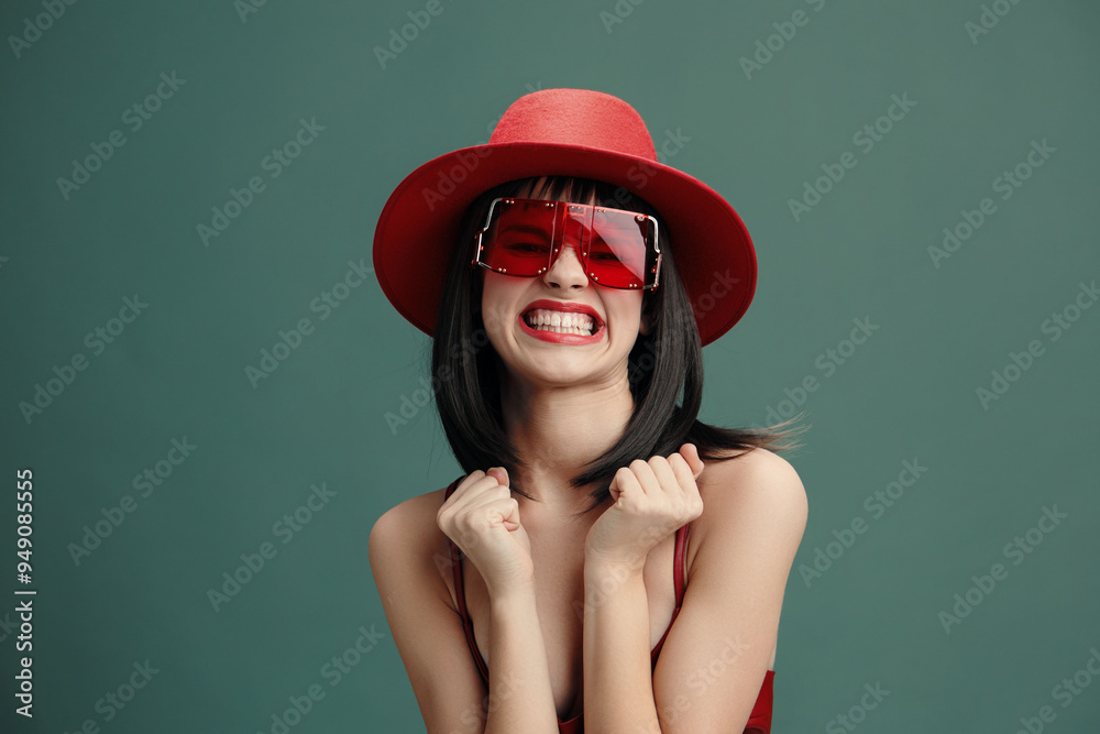 Fototapeta premium Woman in red hat posing with smile, sunglasses, hands on hips, outdoors