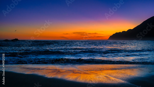 Single  seagull flying over the water at nightfall at White Rock beach, Wairarapa photo