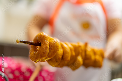 Woman serving skewer of delicious peruvian picarones fritters photo