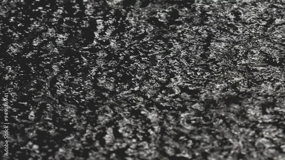 Tokyo, Japan -August 27, 2024: Heavy rain falling on a pool on asphalt pavement at night