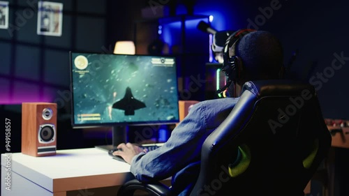 Heartbroken gamer dejected after losing in online multiplayer videogame, being defeated by rivals. Man putting hands on head in frustration after seeing game over screen on gaming pc monitor, camera B