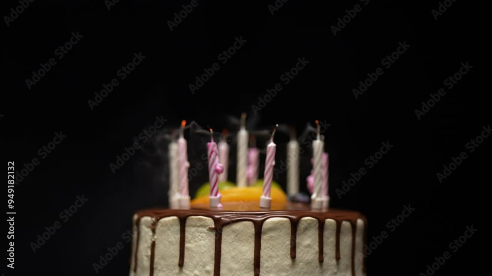 A rotating chocolate-covered birthday cake with candles on top. The candles flicker and slowly go out due to the breeze.