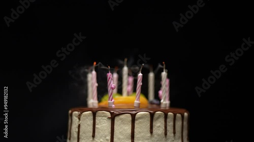 A rotating chocolate-covered birthday cake with candles on top. The candles flicker and slowly go out due to the breeze.